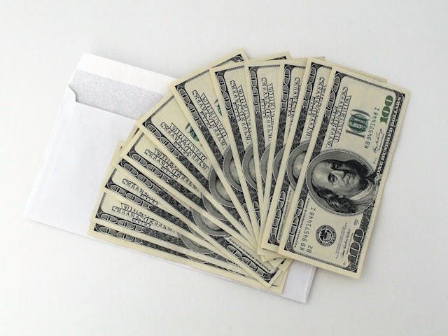 money fanned out over a white envelope