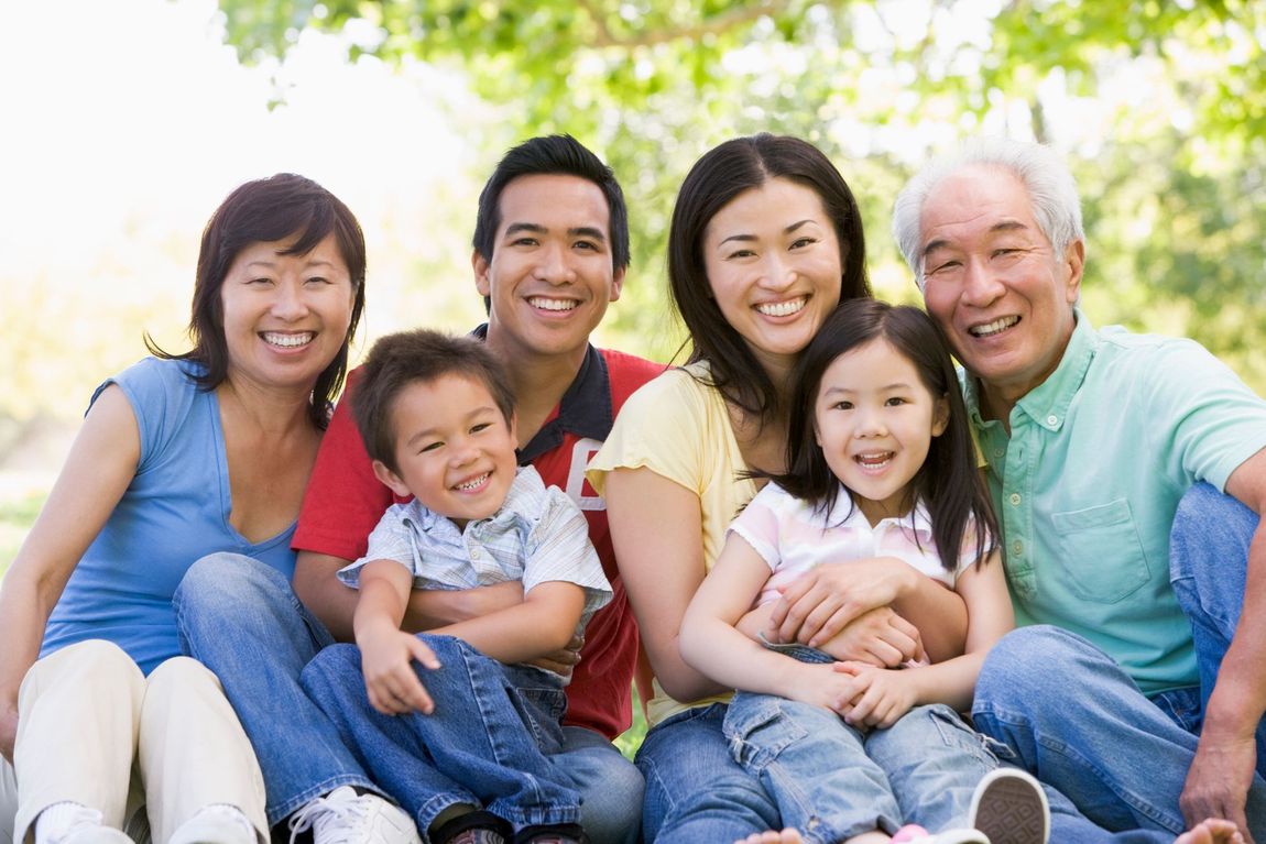 A large family is posing for a picture in a park.