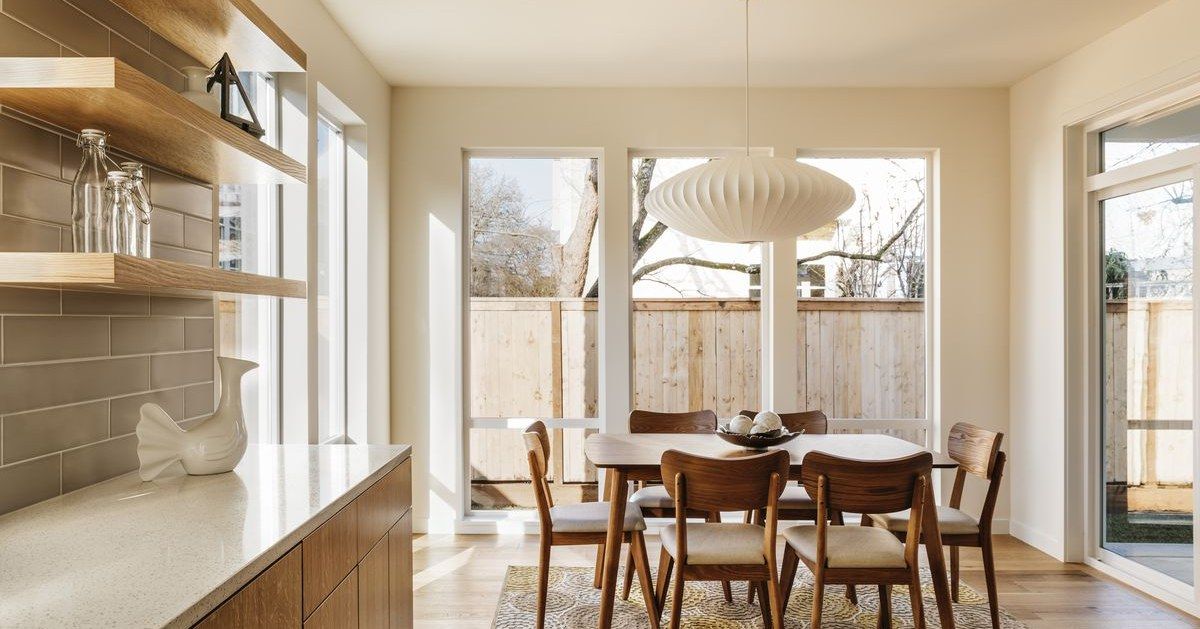 A dining room with a table and chairs and a large window.