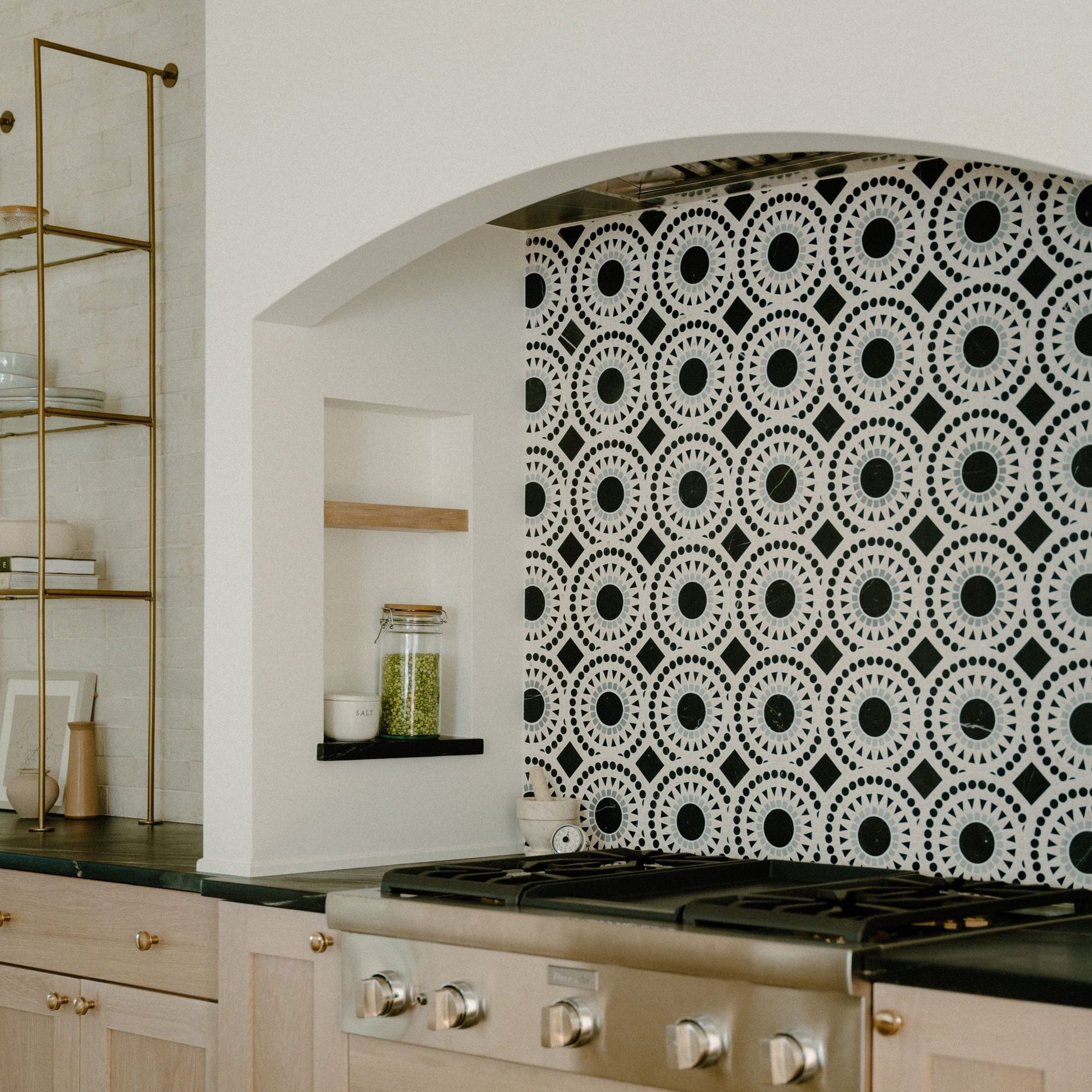 A kitchen with a stove top oven and black and white tiles