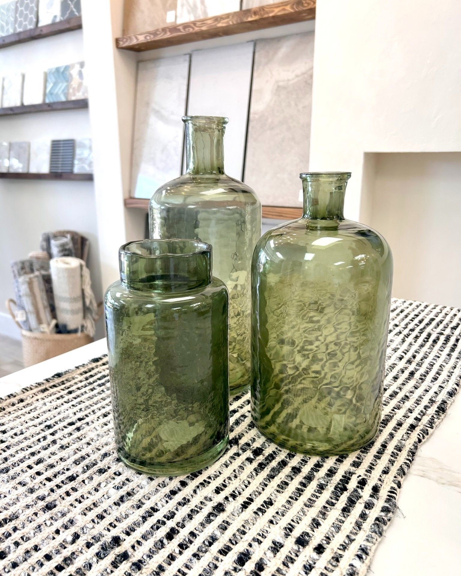 Three green glass vases are sitting on a table.