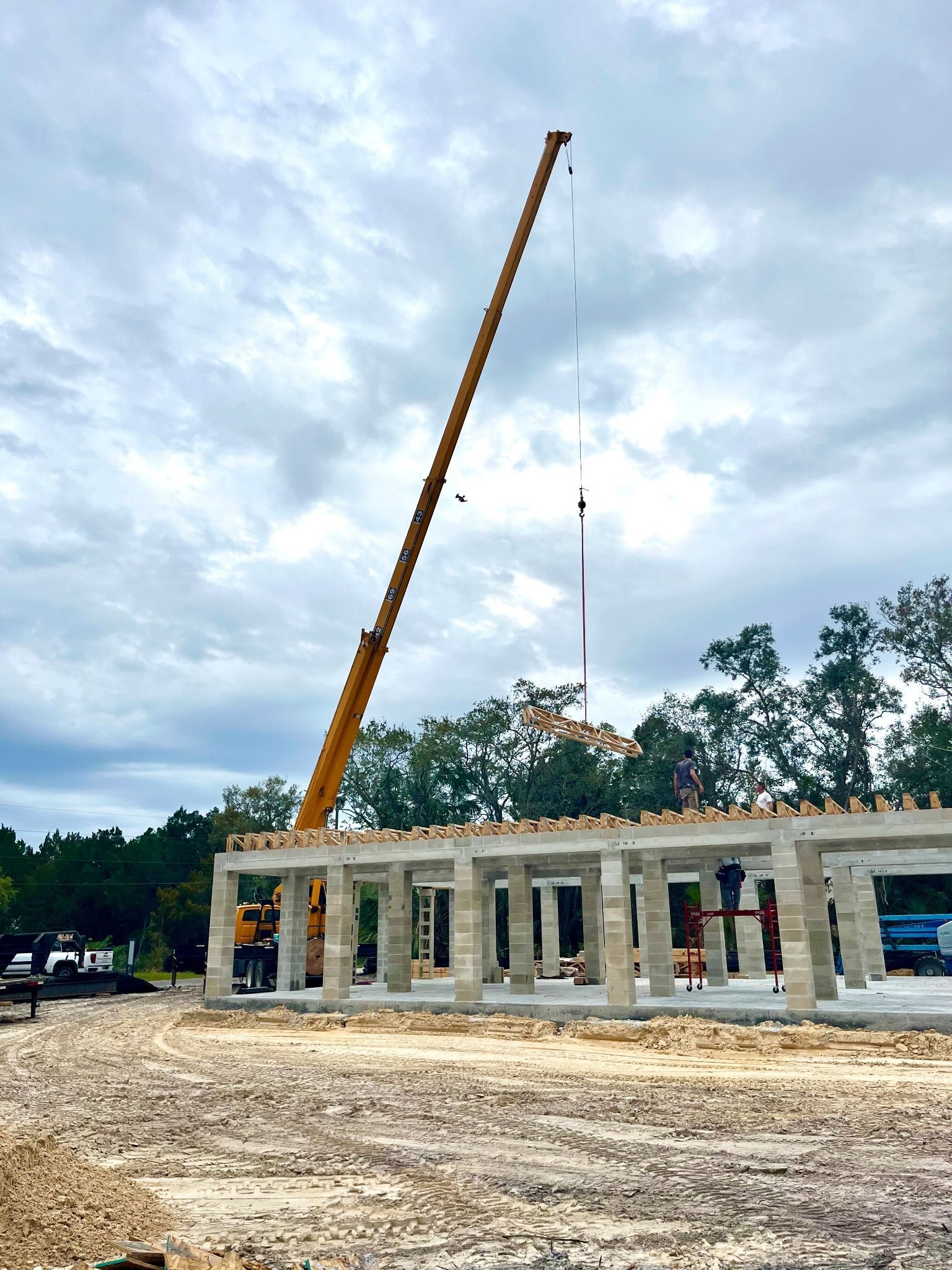 A large yellow crane is lifting a flag over a building under construction