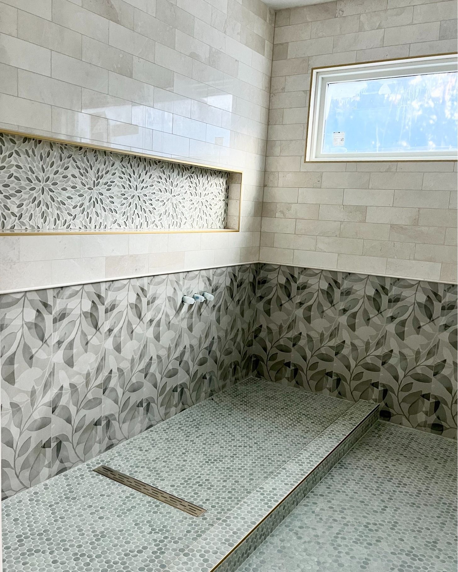 A bathroom with a walk in shower and a window.
