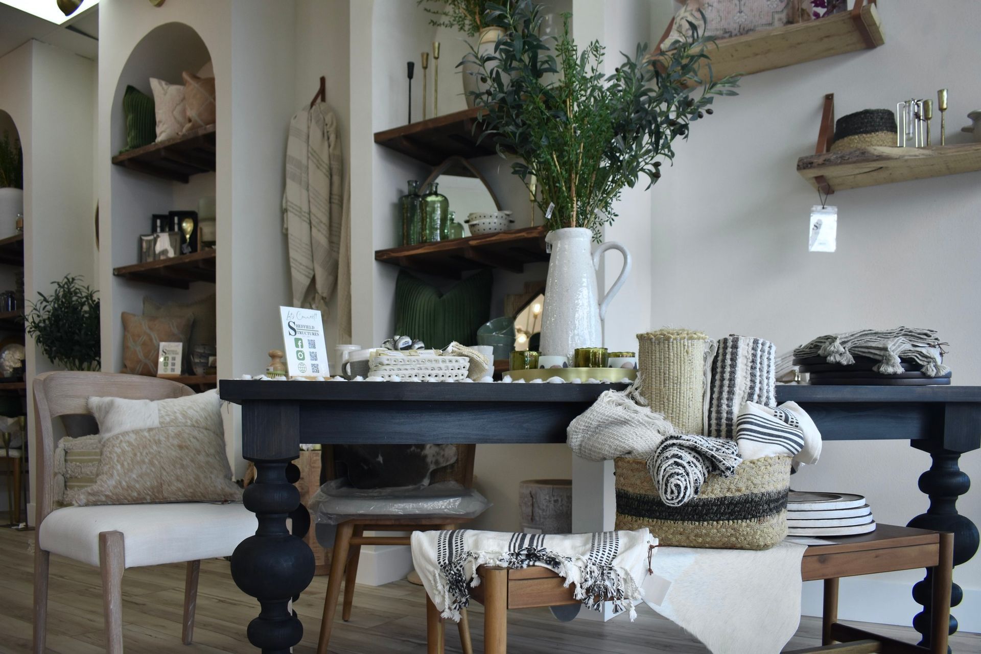 A living room with a table and chairs and a vase of flowers on it.