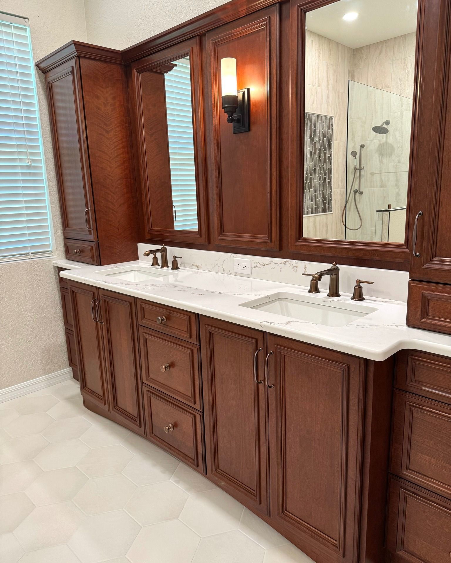 A bathroom with two sinks , two mirrors , and wooden cabinets.