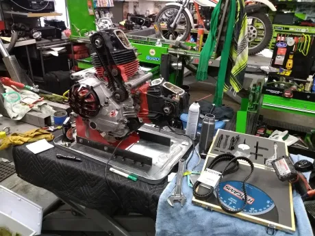 A motorcycle engine is sitting on top of a table in a garage.