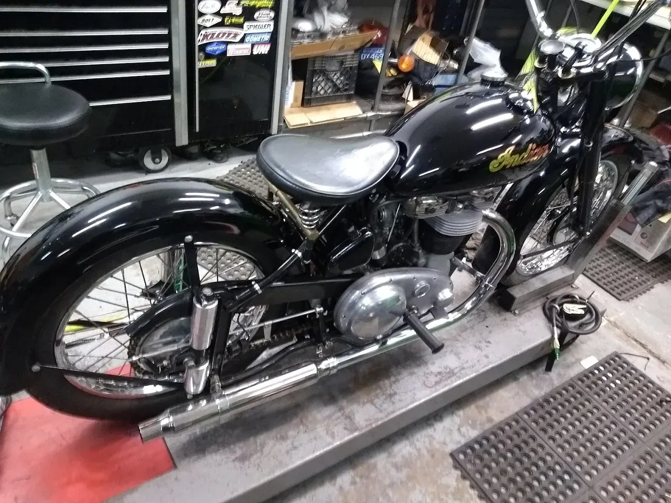 A black motorcycle is parked on a platform in a garage.