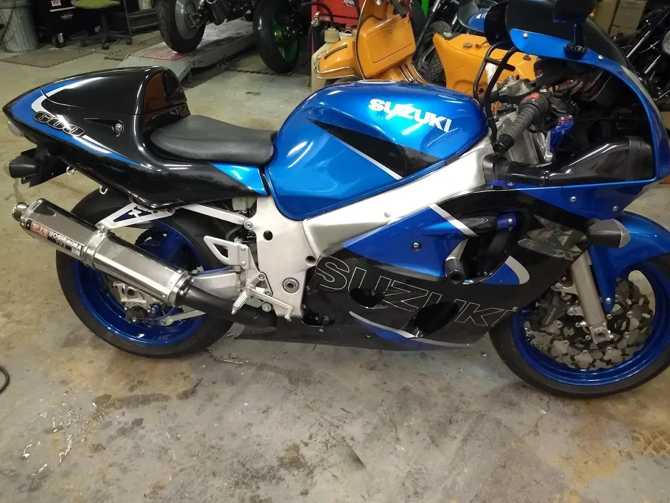 A blue and black suzuki motorcycle is parked in a garage