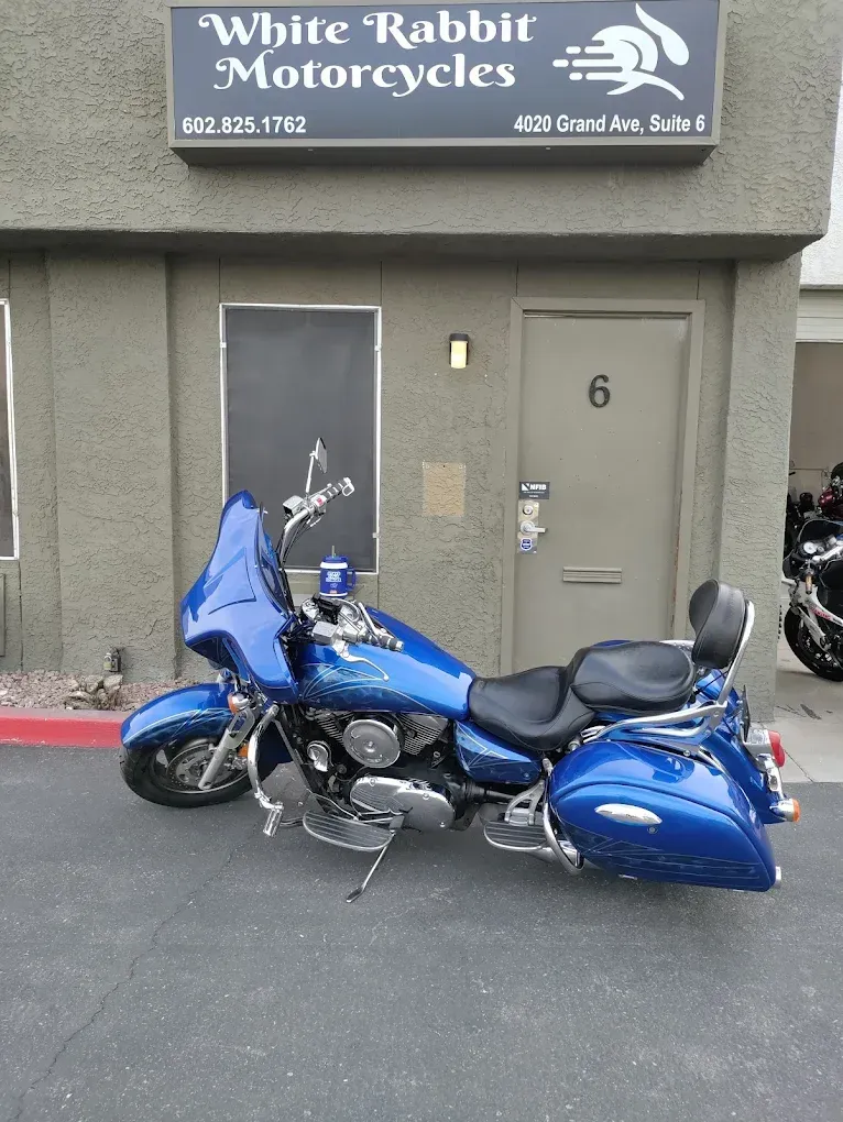 A blue motorcycle is parked in front of white rabbit motorcycles