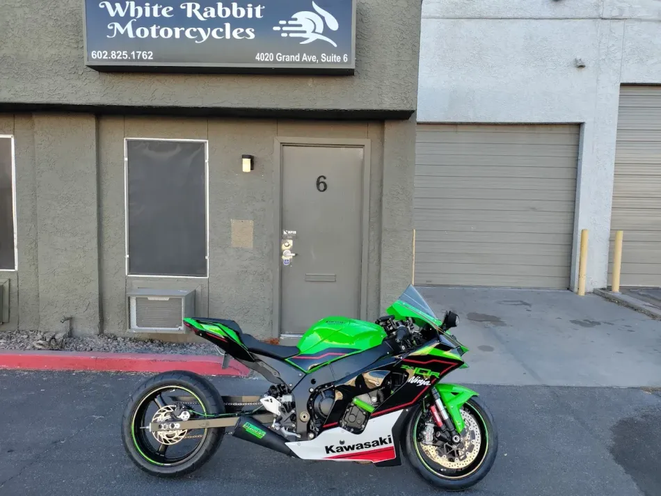 A green motorcycle is parked in front of a building that says white rabbit motorcycles