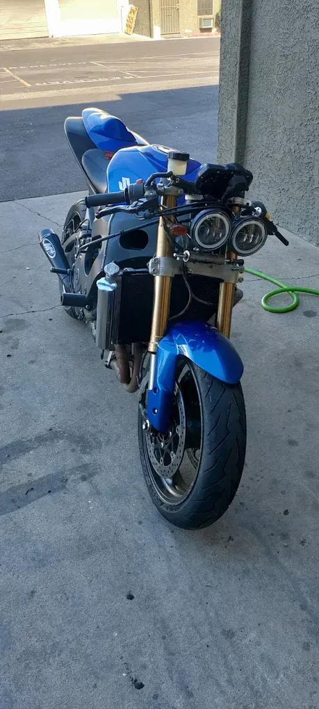 A blue motorcycle is parked on the sidewalk next to a building.