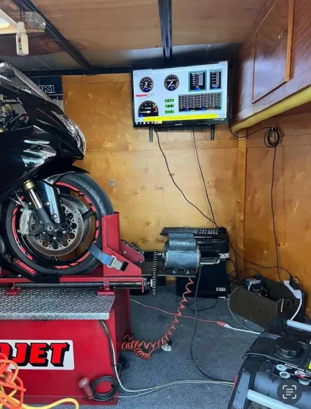 A motorcycle is sitting on a wheel balancing machine in a garage.