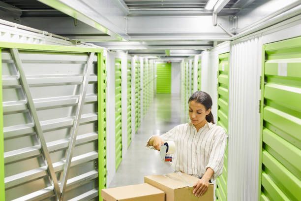 A woman is packing boxes in a storage room.