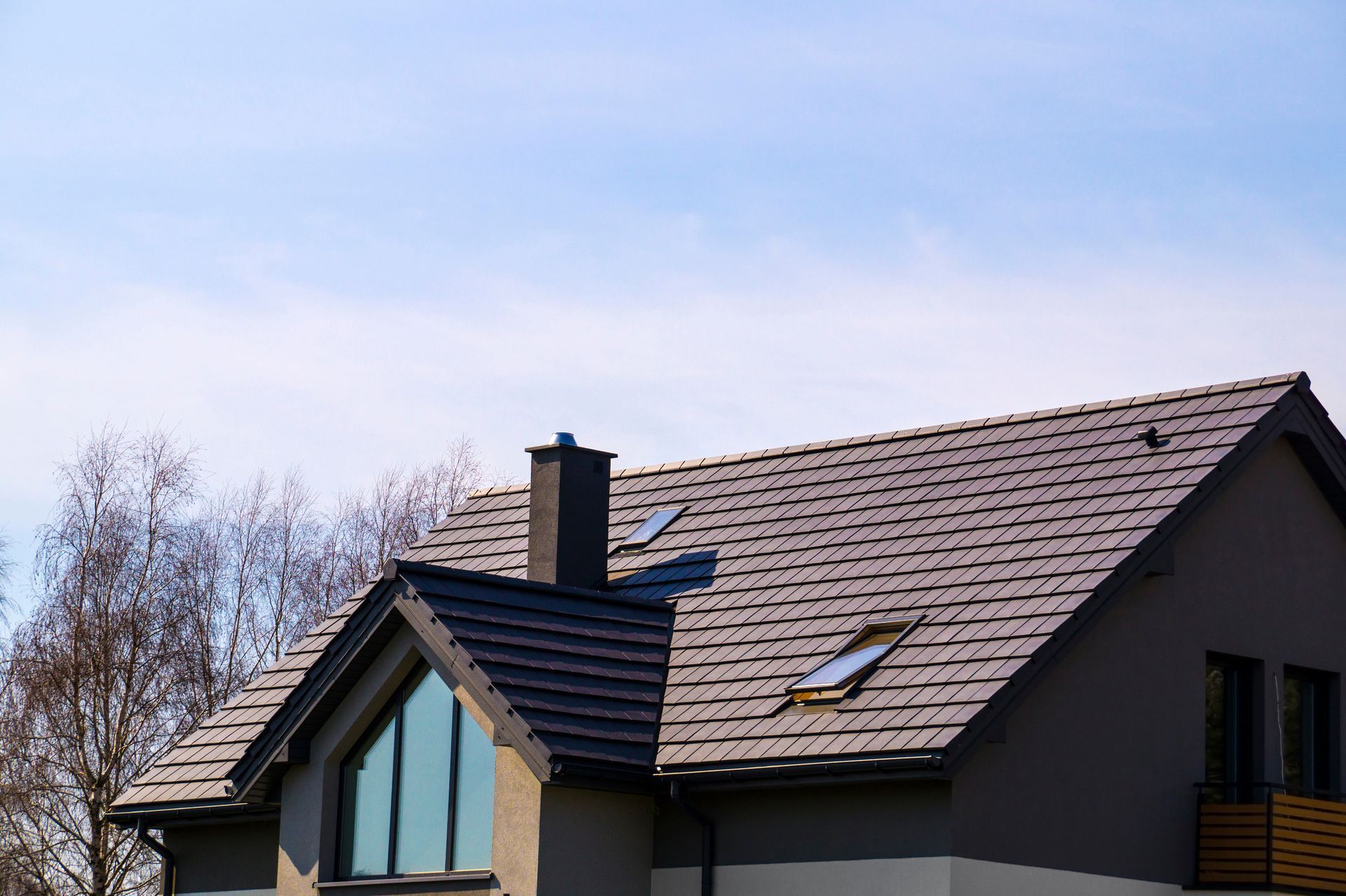 Modern house roof with skylights and a chimney under a blue sky