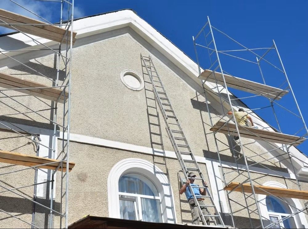 Scaffolding and a ladder on the exterior of a stucco building under construction. Scaffolding and a ladder on the exterior of a stucco building under construction.