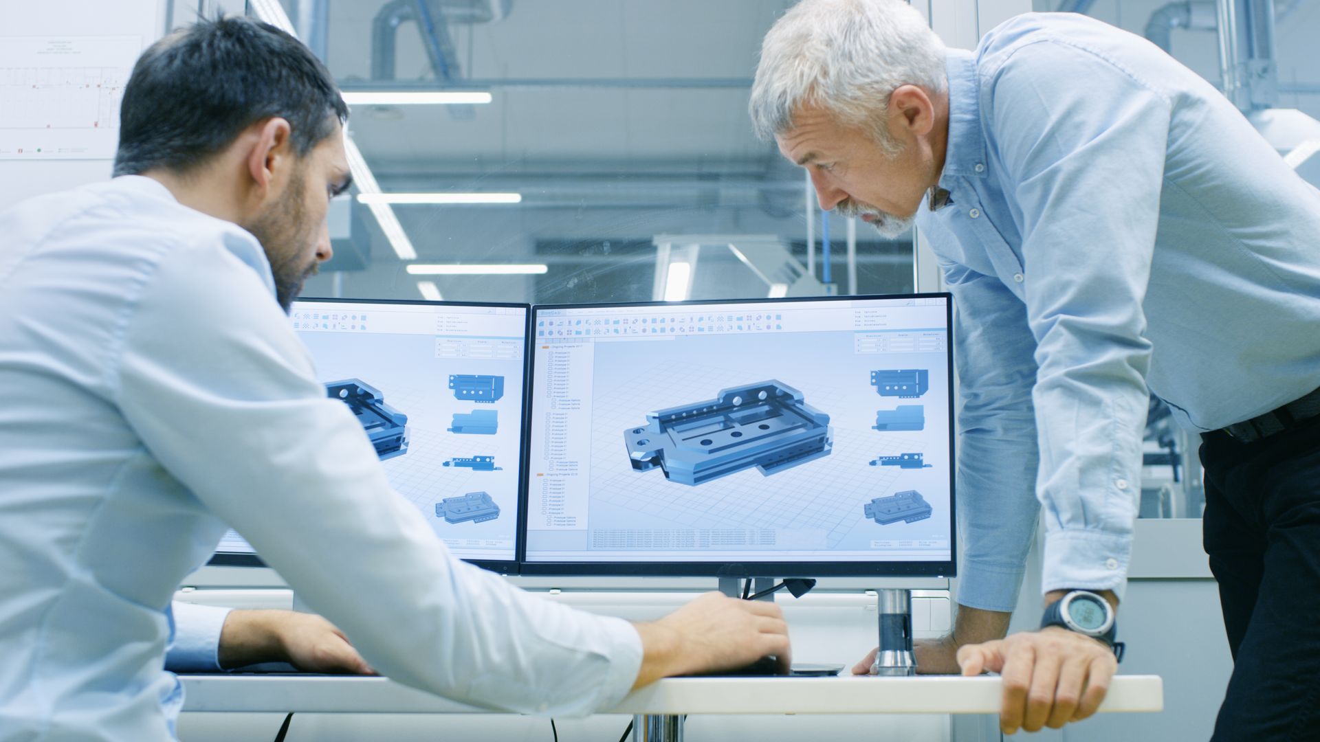 Two men are looking at a computer screen in a factory.