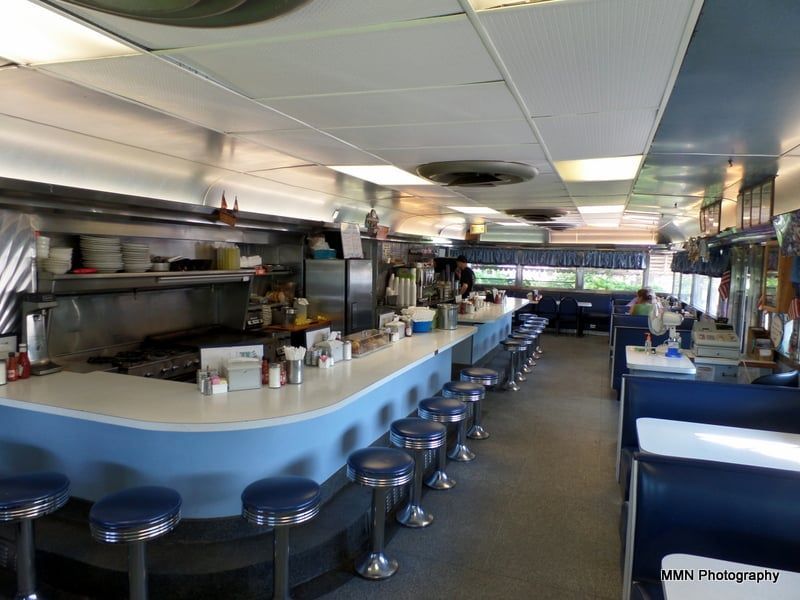 The inside of a diner with a long counter and stools.