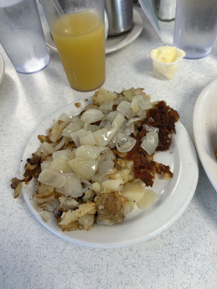 A plate of food is on a table next to a glass of orange juice.