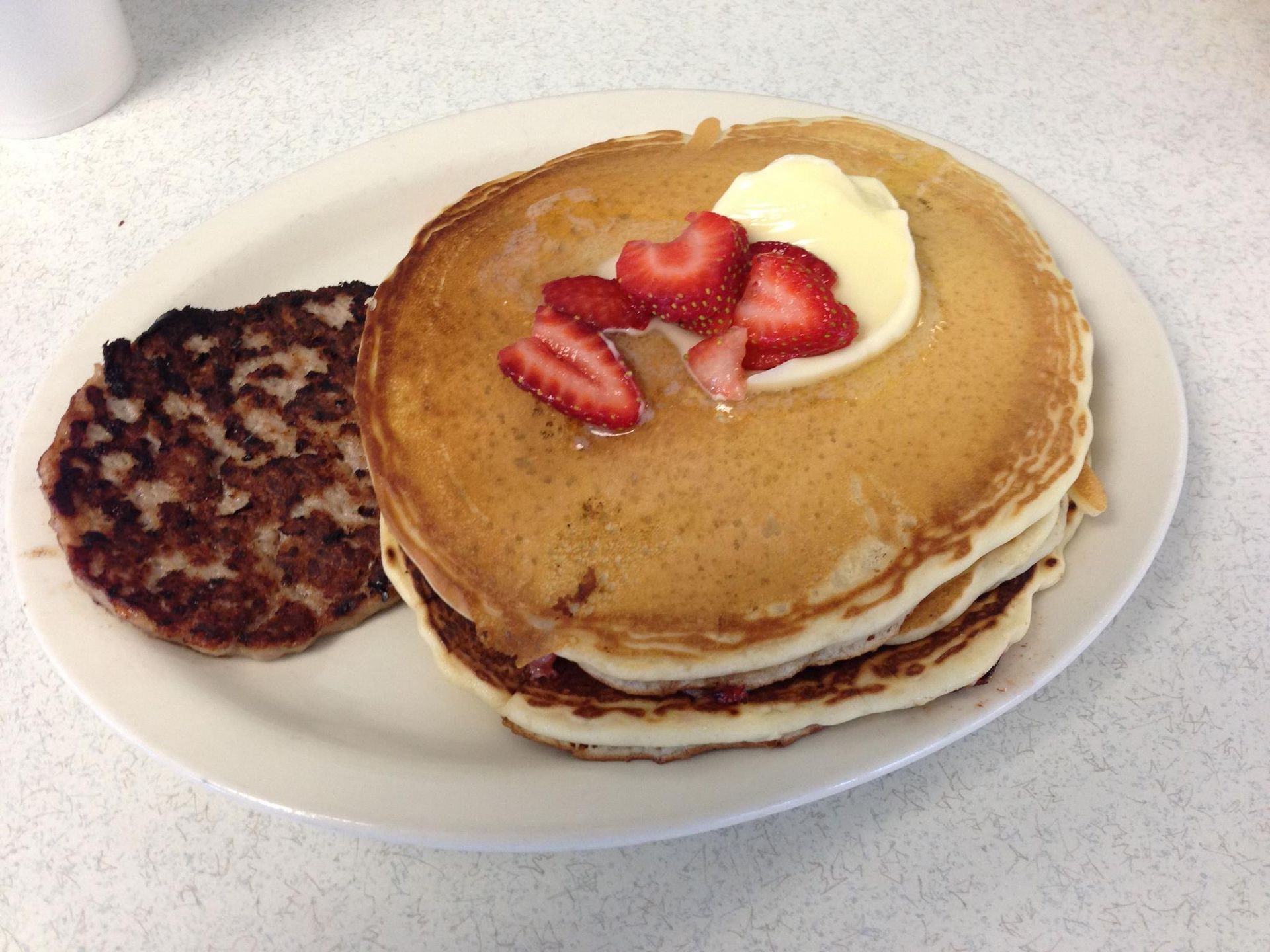 A plate of pancakes with strawberries and whipped cream