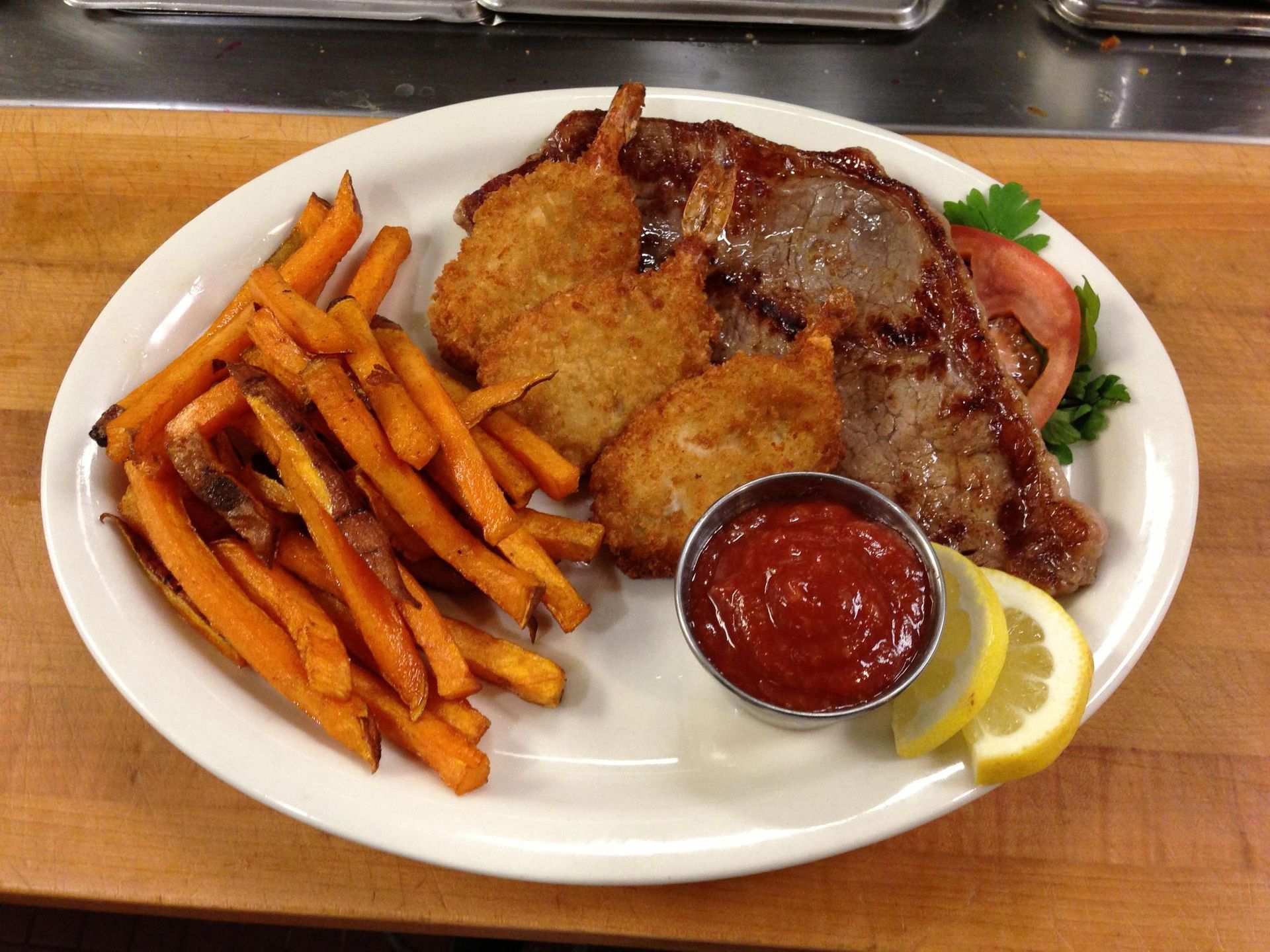 A white plate topped with meat and french fries on a wooden table