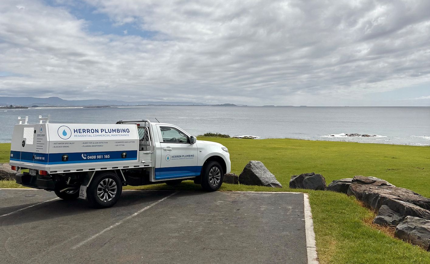 A Person is Holding a Pipe in a Hole in the Ground — Herron Plumbing in Shellharbour, NSW