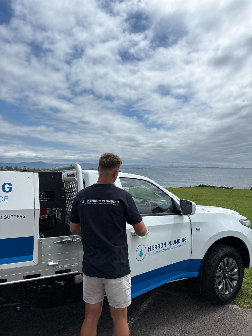 A Man is Standing Next to a White Truck — Herron Plumbing in Flinders, NSW