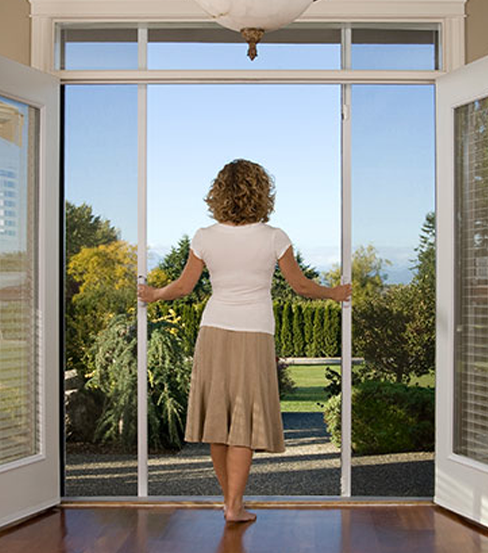 Woman looking outside of double door screen calling for retractable screens in Melbourne