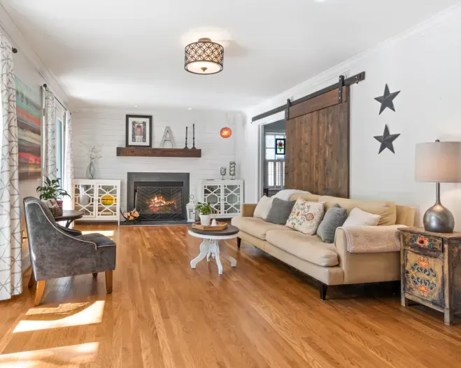 Living room with a fireplace, hardwood floors, and a barn door.