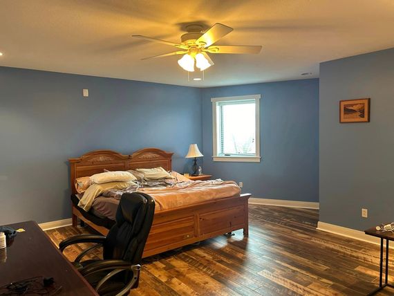 A bedroom with a bed , desk , chair and ceiling fan.