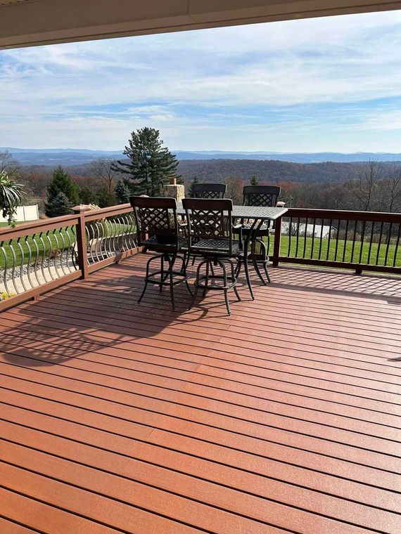 A large wooden deck with a table and chairs on it.