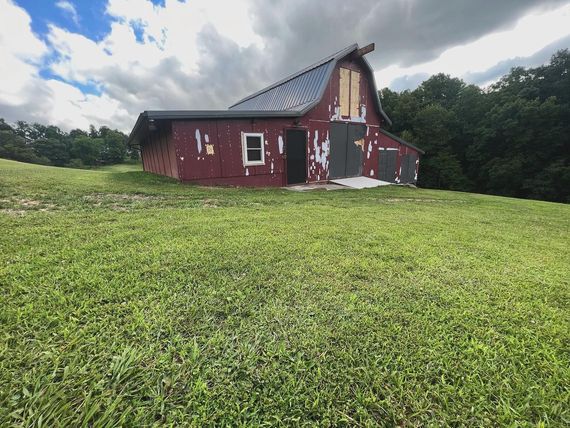 A red barn is sitting in the middle of a grassy field.