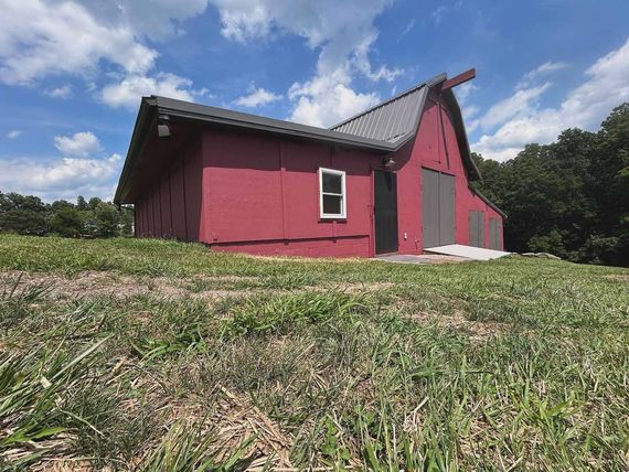 A red barn is sitting in the middle of a grassy field.