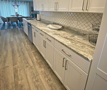 A kitchen with white cabinets and granite counter tops.