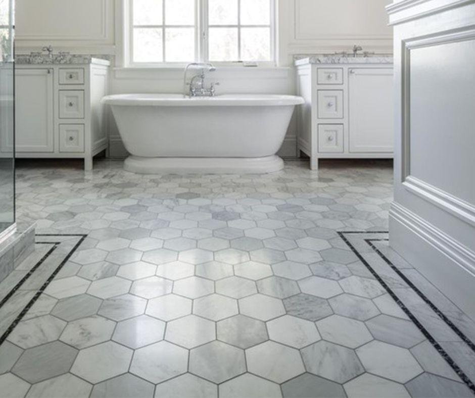 There is a bathtub in the bathroom with a hexagonal tile floor.