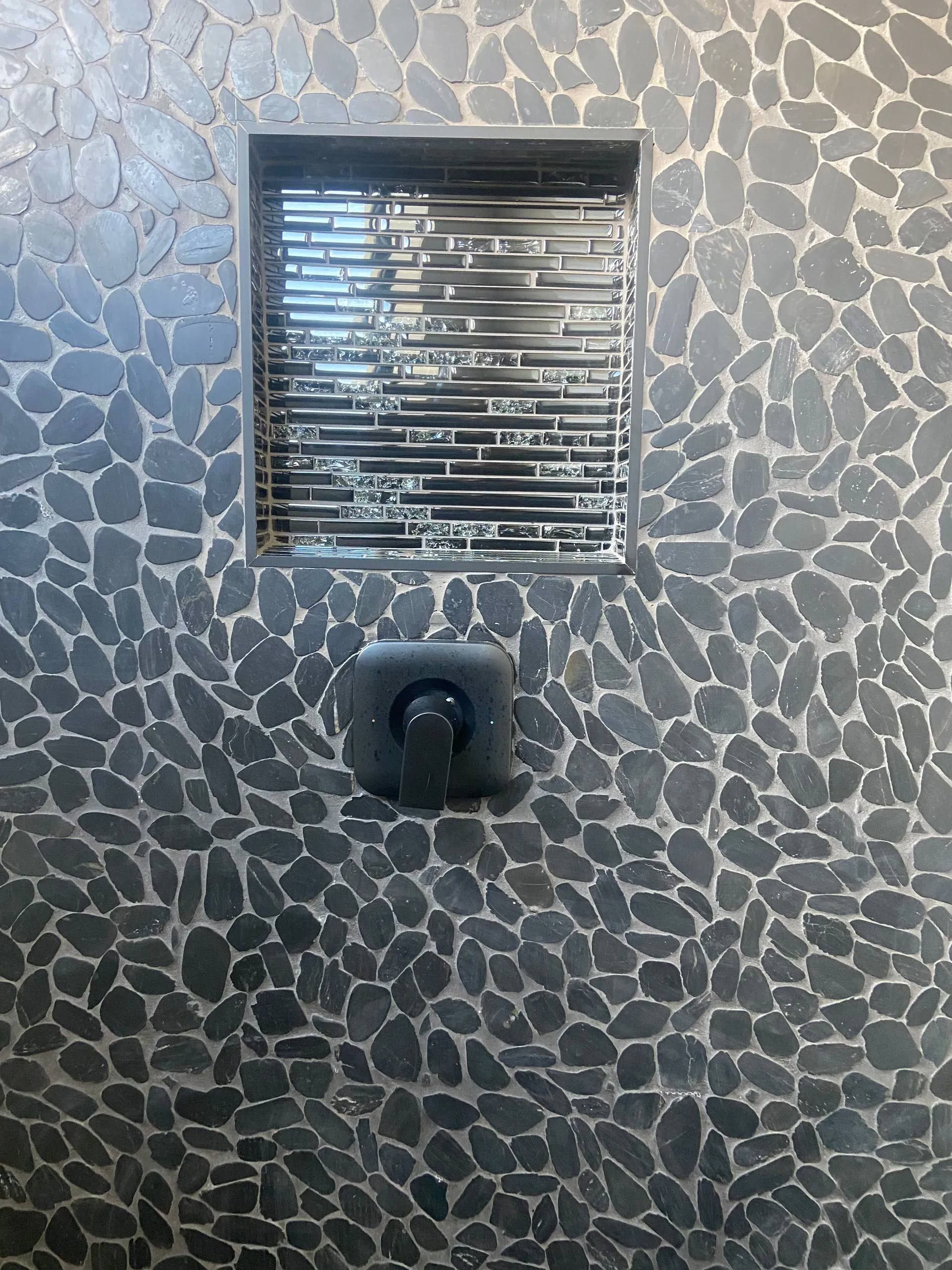 A black tiled wall with a window in it.