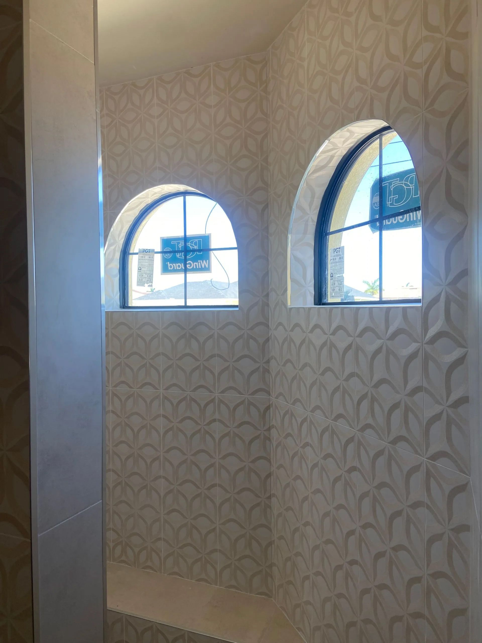 A bathroom with two arched windows on the wall.