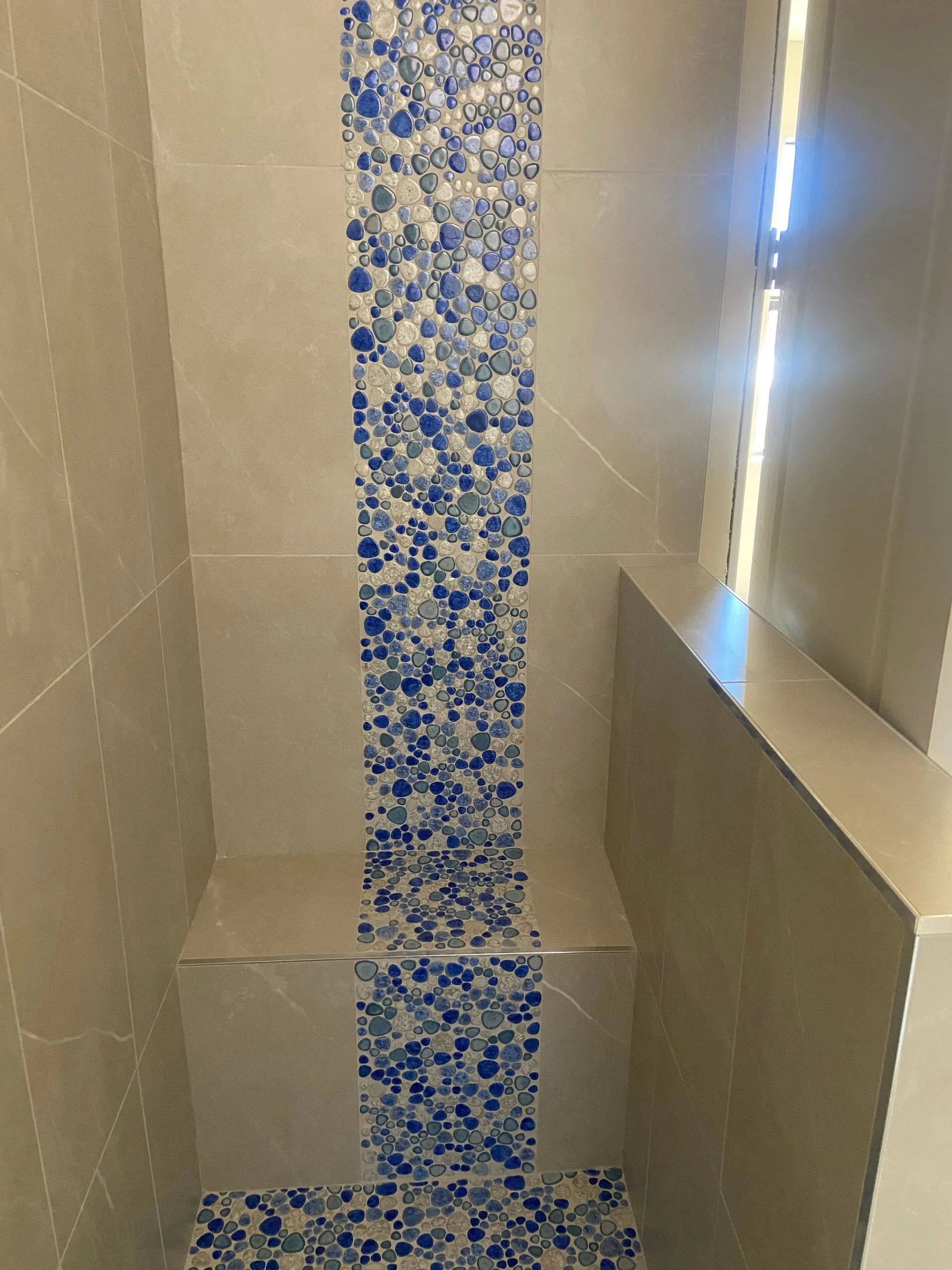 A shower with blue and white tiles on the wall and floor.
