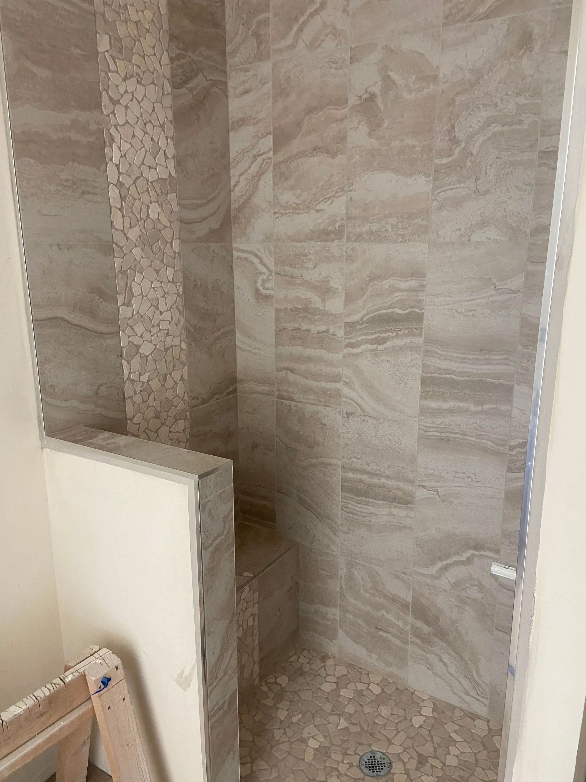 A bathroom with a walk in shower and tiled walls.