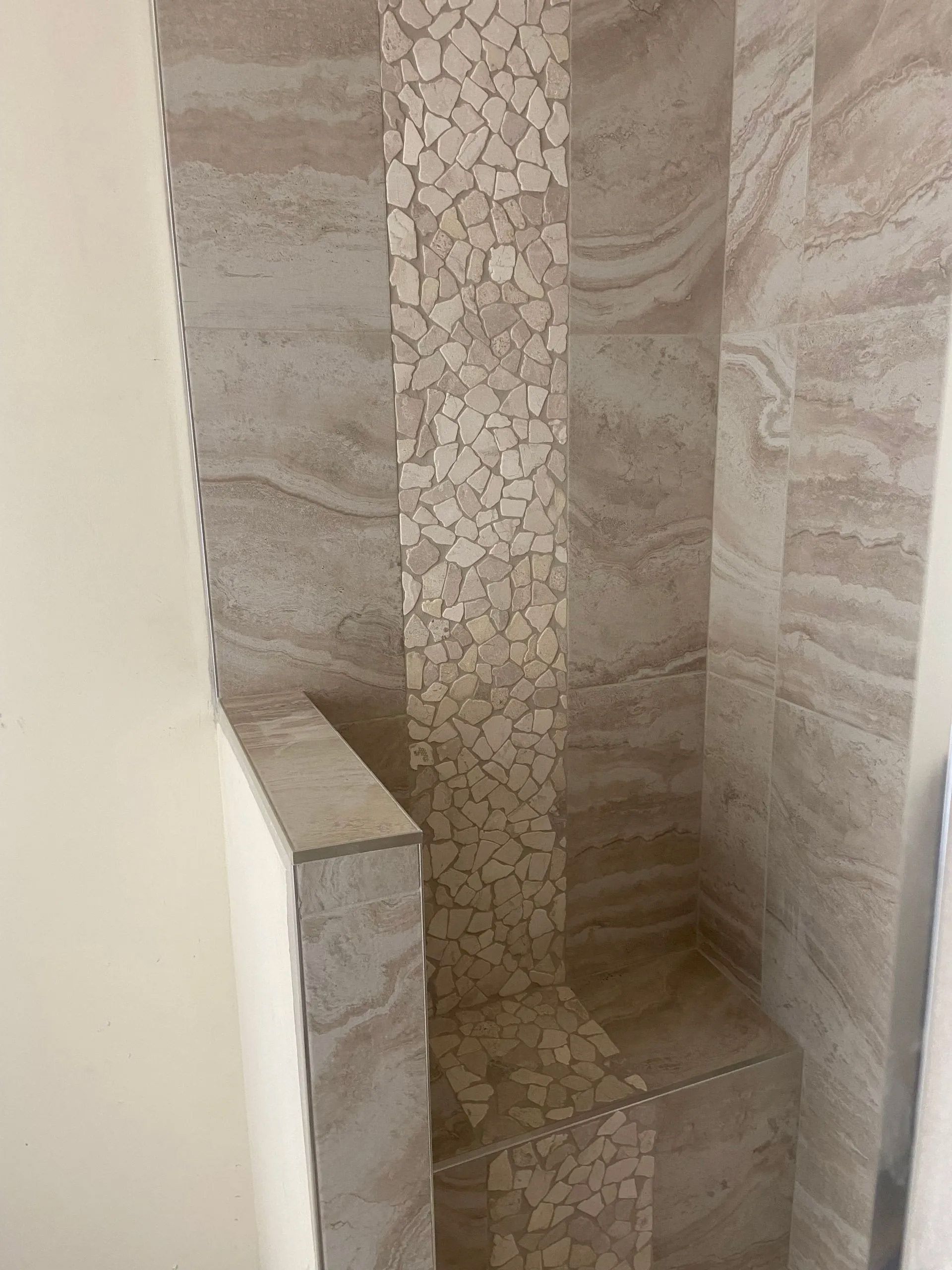 A bathroom with a walk in shower and a tiled wall.