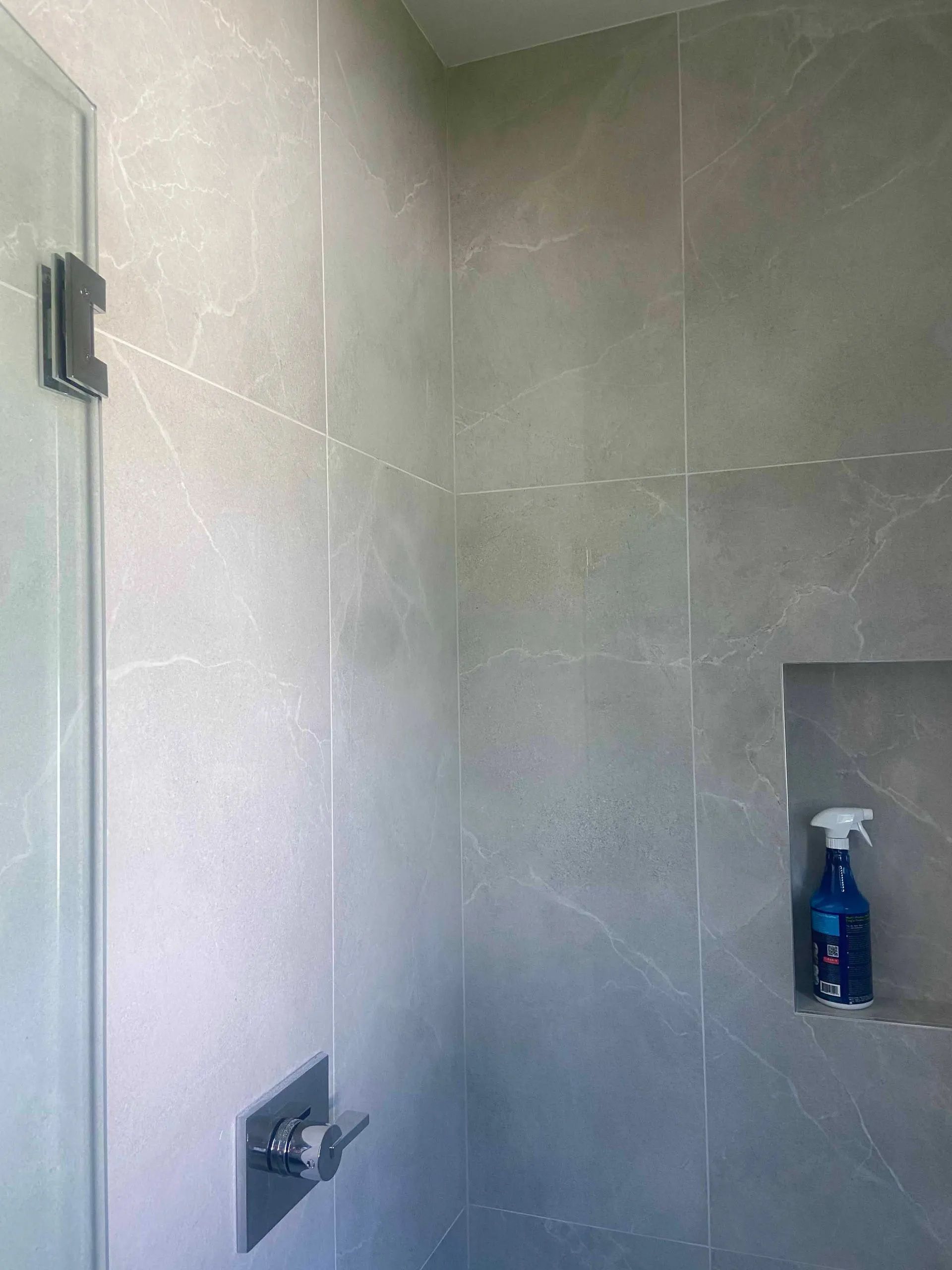 A shower with a glass door and a soap dispenser in the corner.