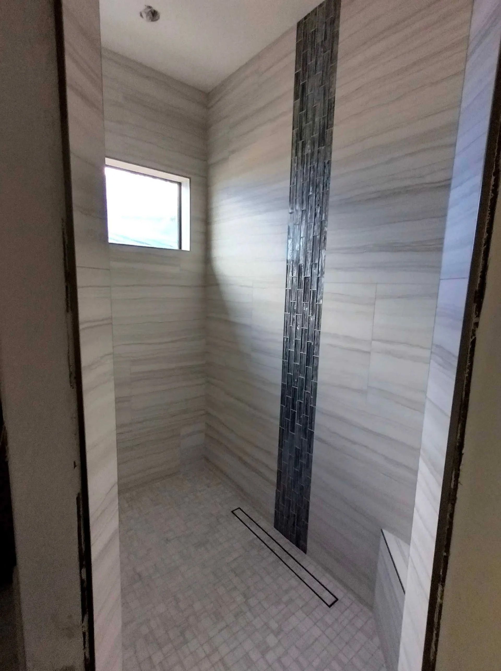 A bathroom with a walk in shower and a window.