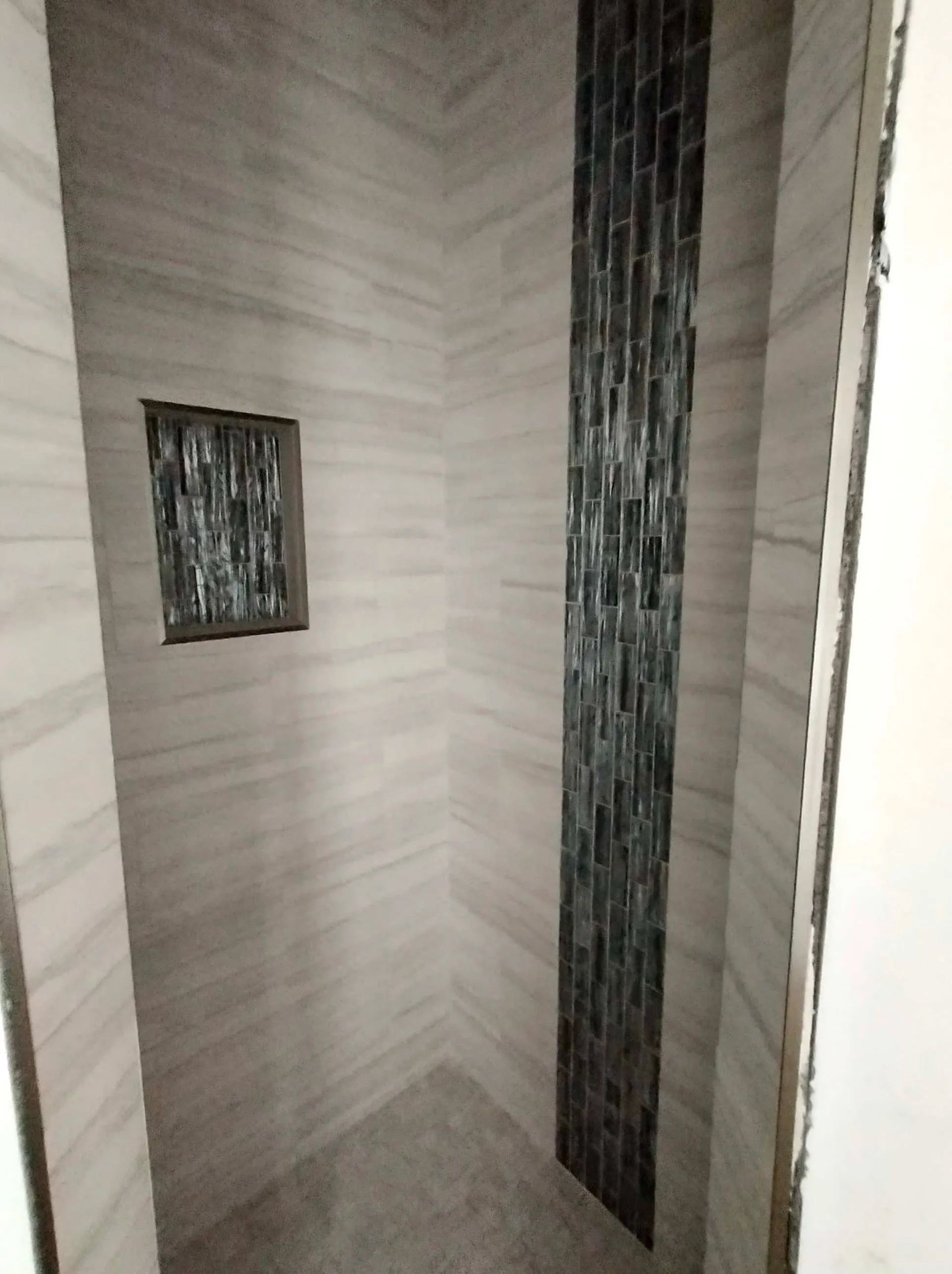 A bathroom with a walk in shower and a tiled wall.
