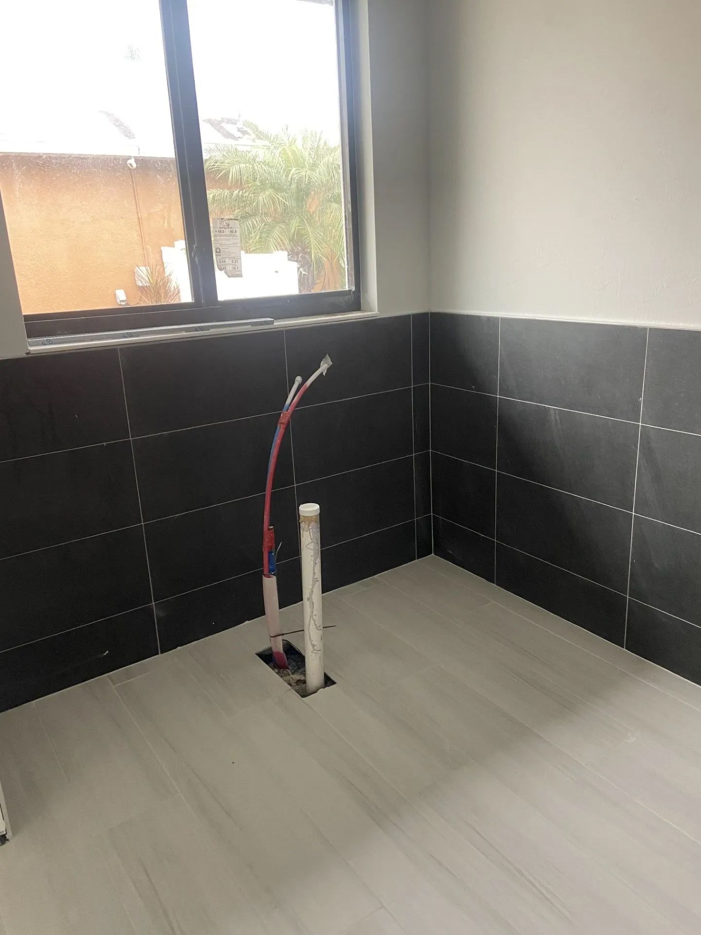 A bathroom with black tiles and a window.