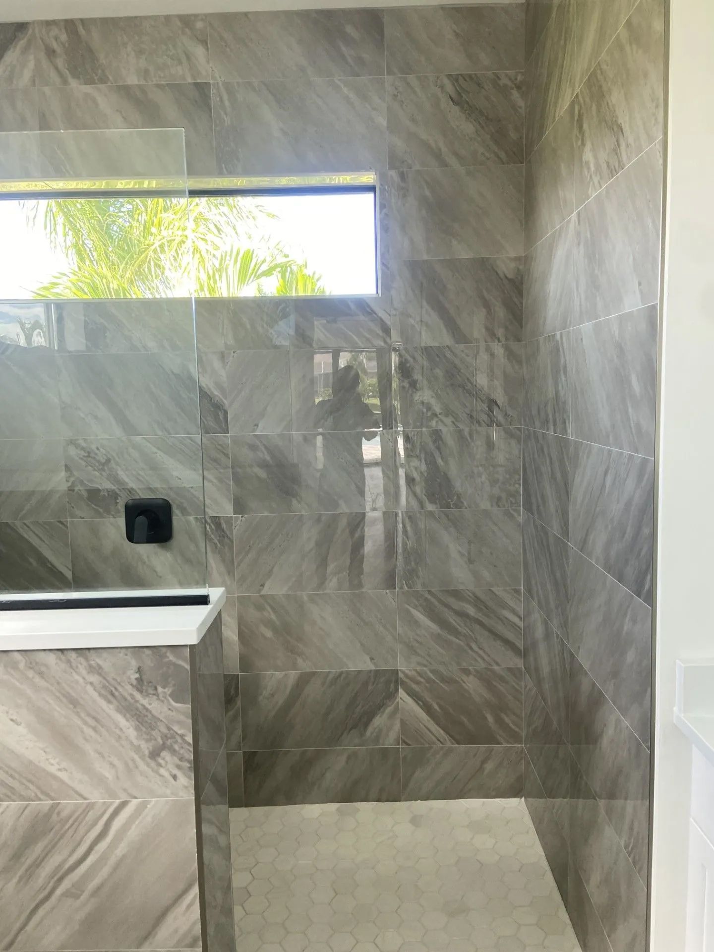 A bathroom with a walk in shower and a window.