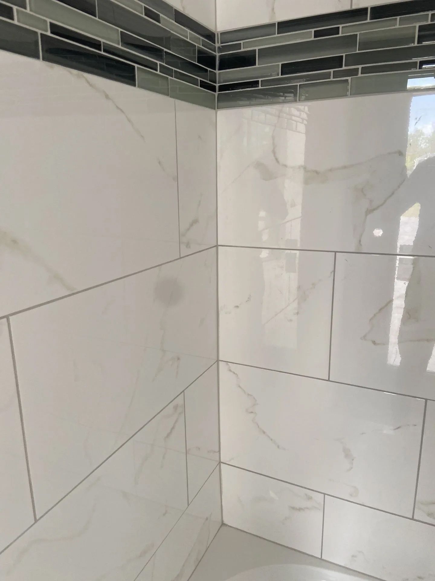 A bathroom with white tiles and a gray tile border.