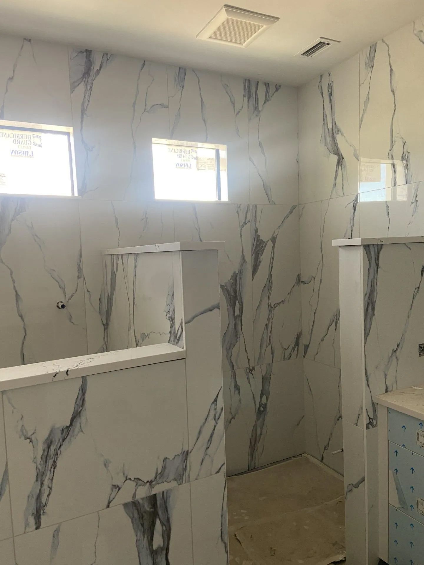 A bathroom with marble tiles and a walk in shower.