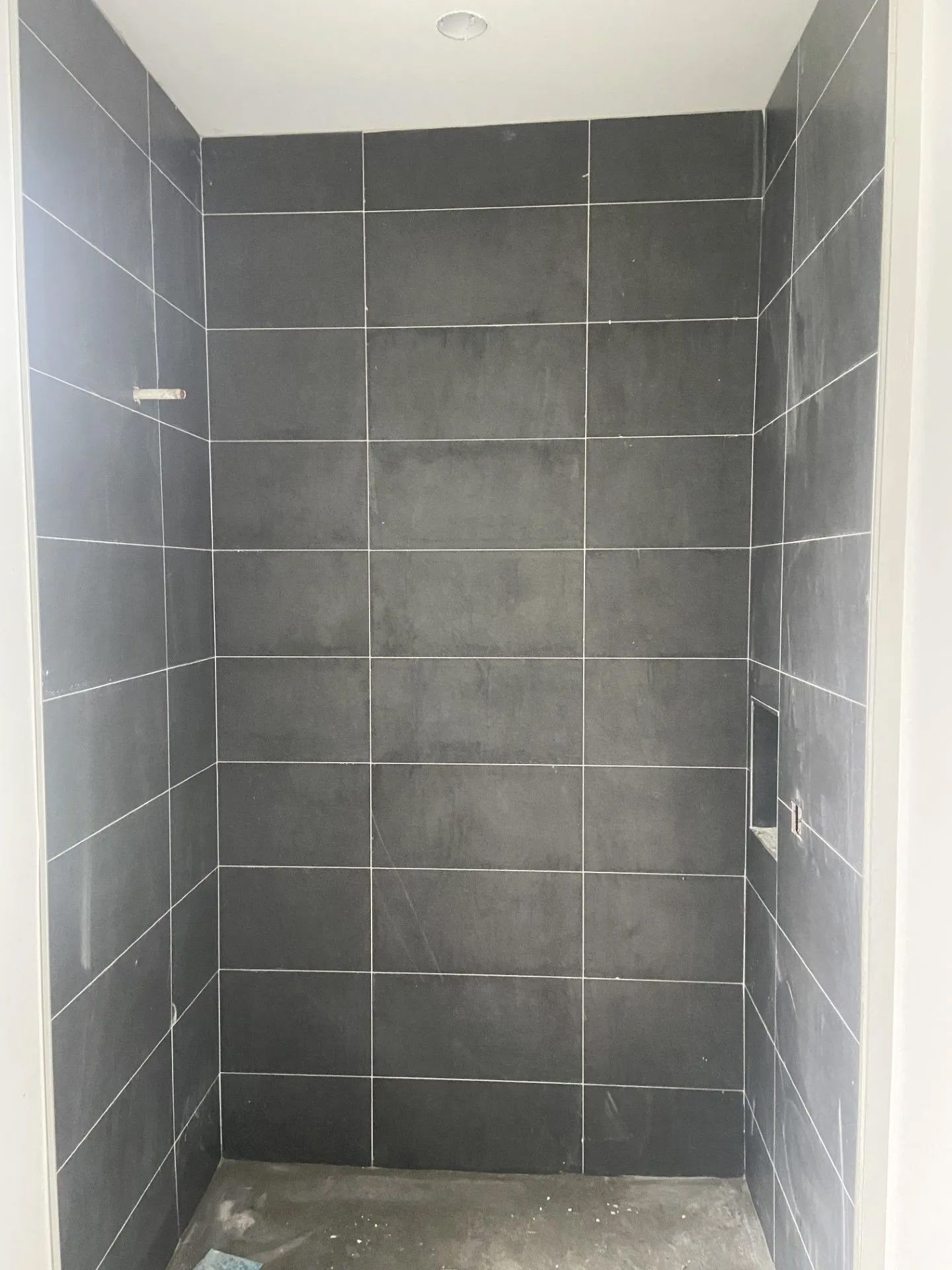 A bathroom with black tiles on the walls and floor.