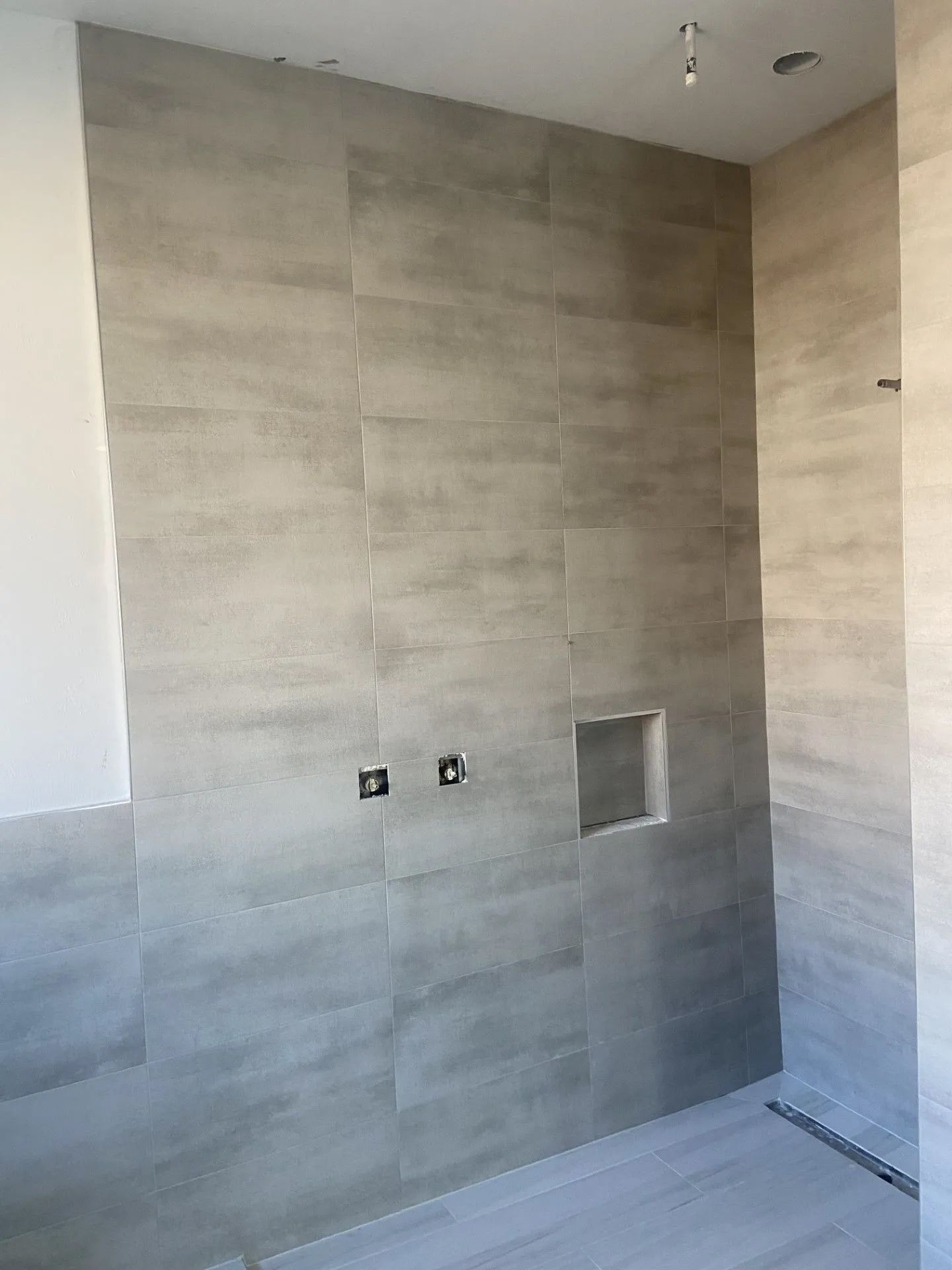 A bathroom with a shower stall and a niche in the wall.