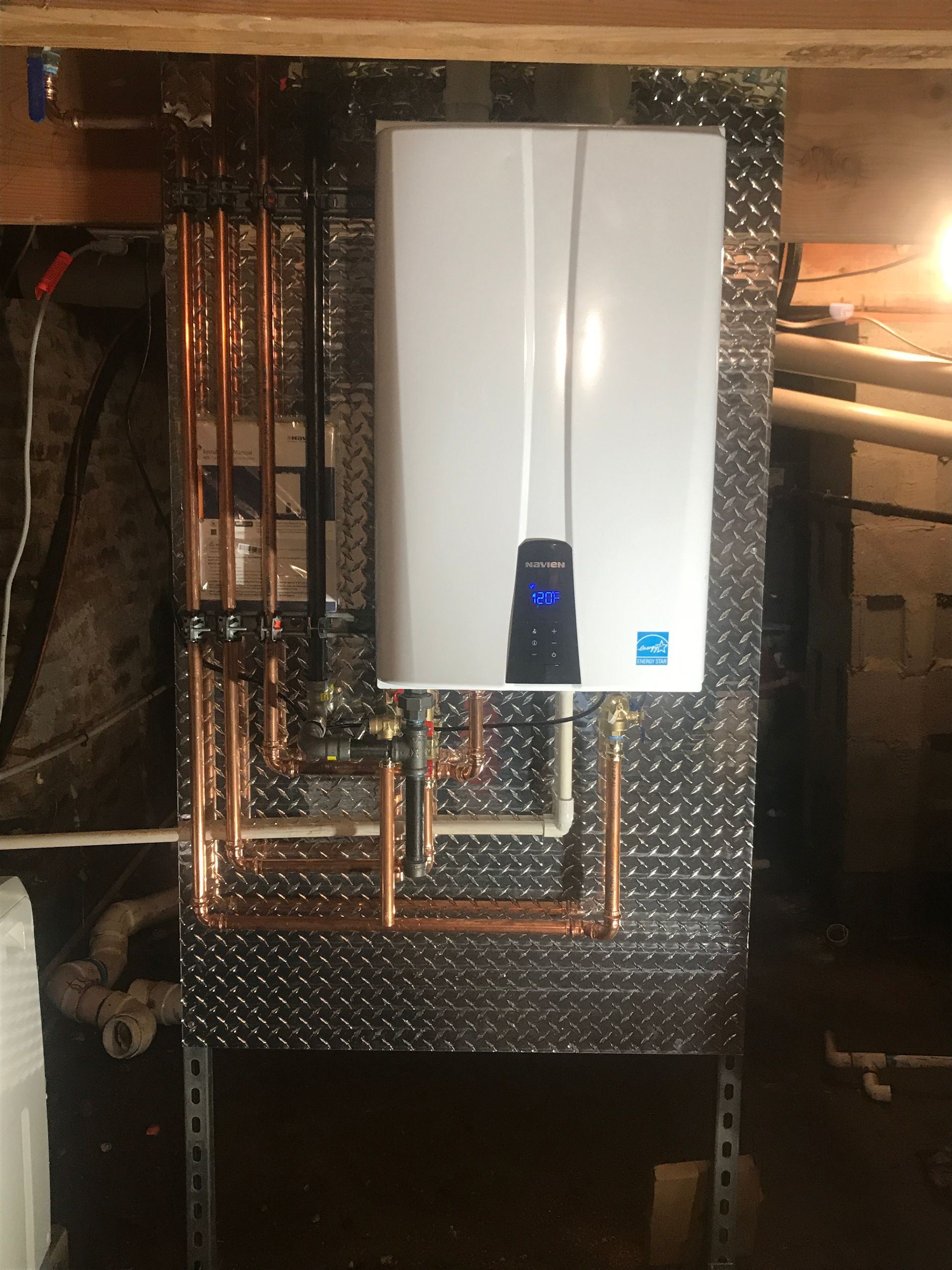 A water heater is mounted to a wall with copper pipes