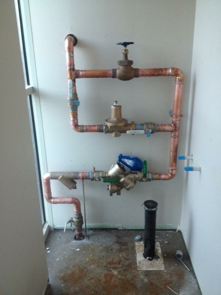 Copper pipes are lined up against a white wall
